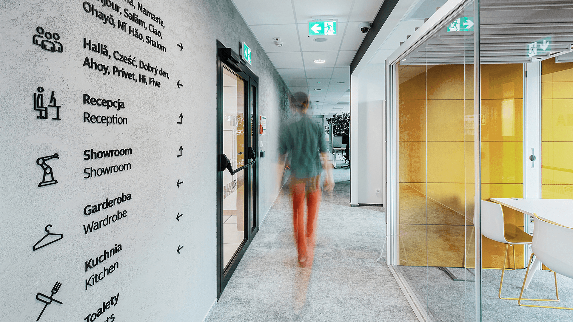 Wayfinding signage designed for an office interior, with a person walking down a corridor